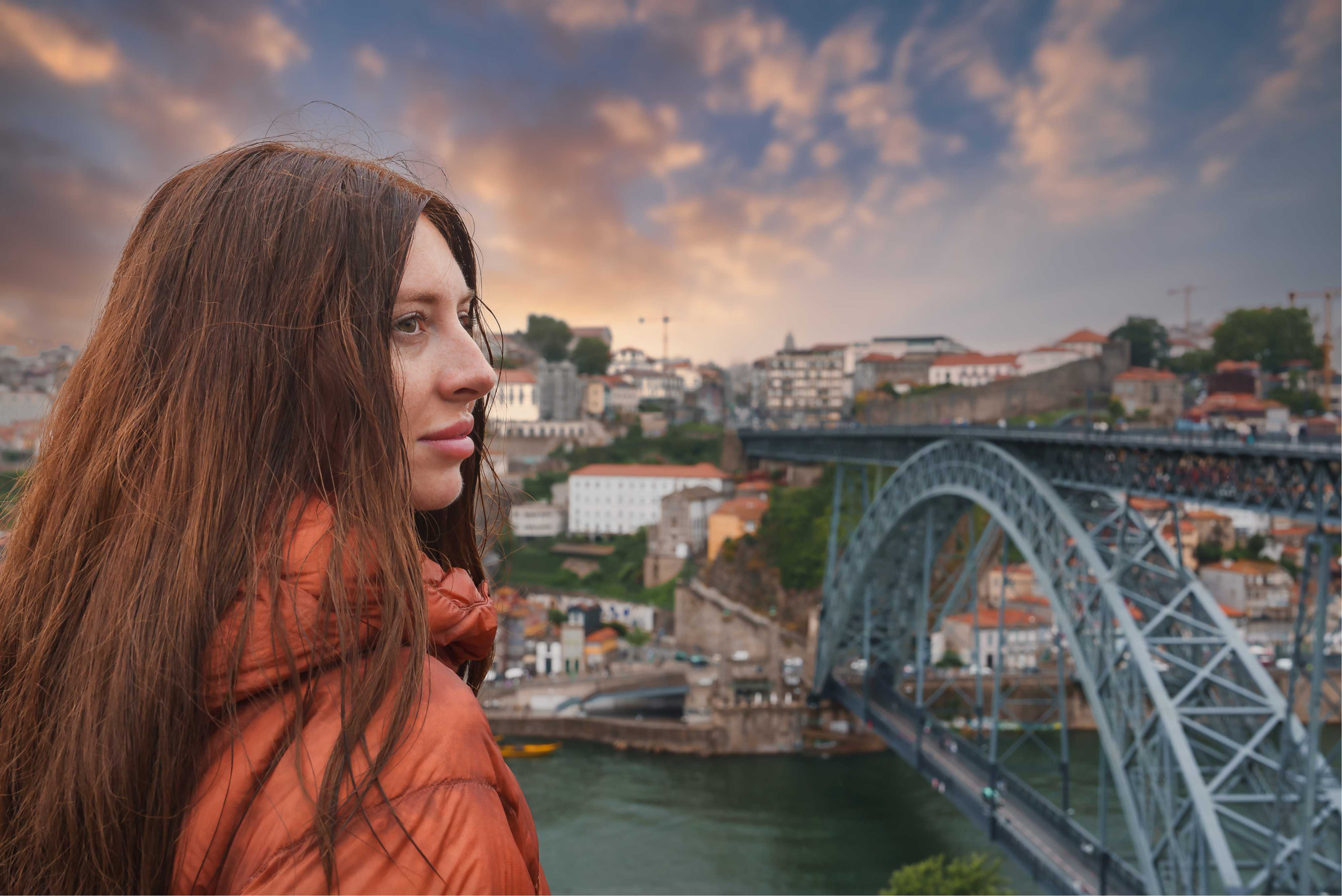 young-woman-orange-jacket-posing-by-dom-luis-i-bridge-sunset-porto